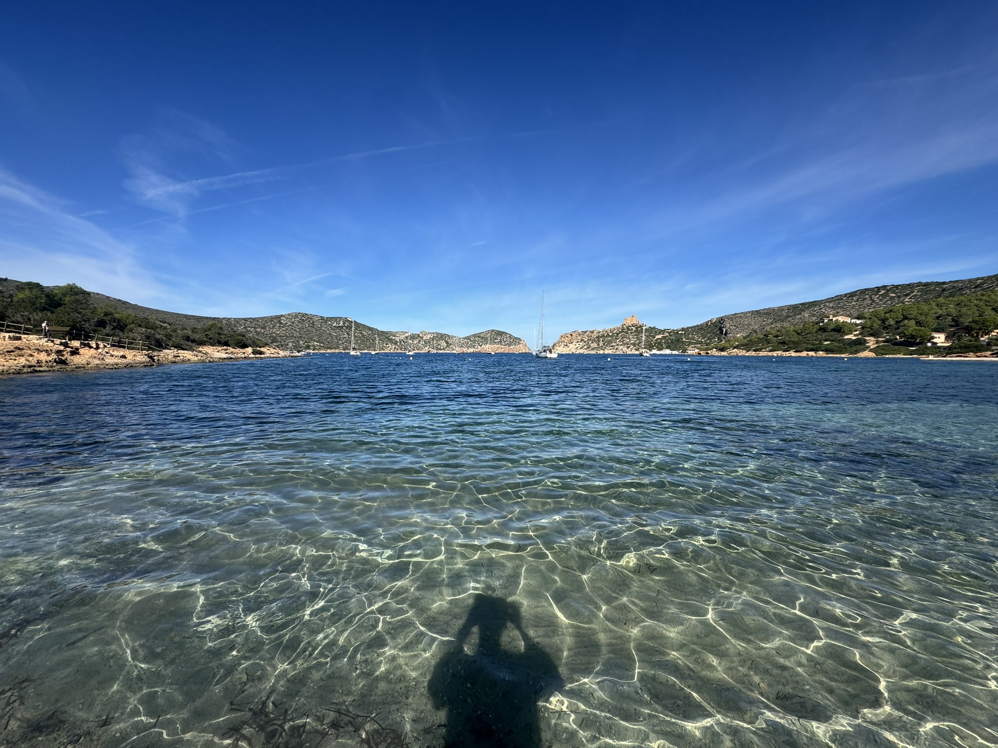 Glasklares Wasser in einer Bucht auf Cabrera mit Blick auf die Küste und die Burg.