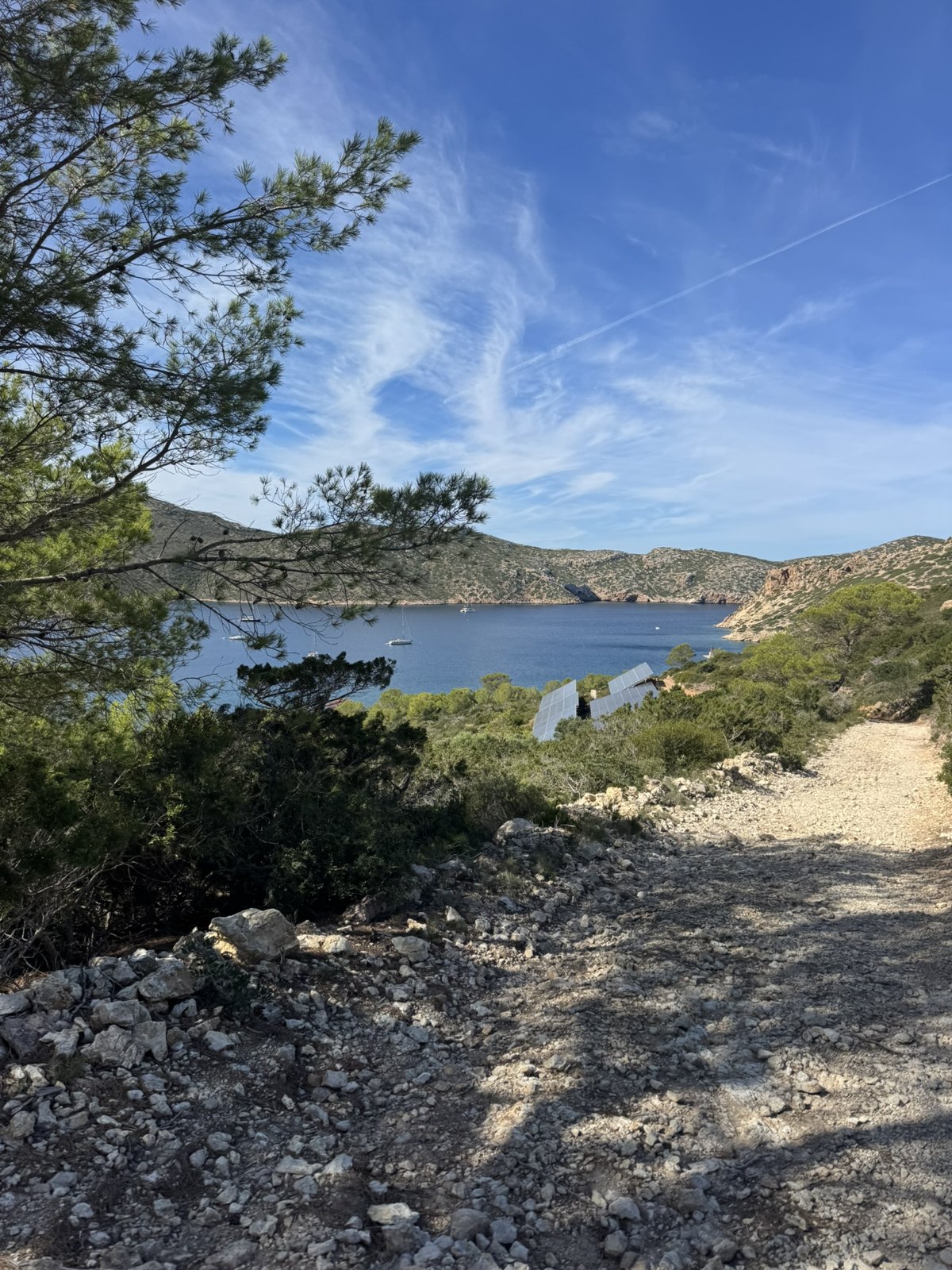 Steiniger Wanderweg auf Cabrera mit Blick auf die Bucht und das Meer.