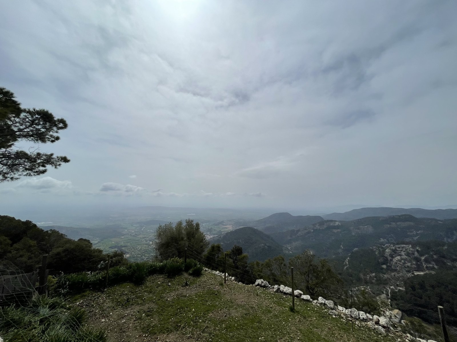 Blick von Alaró über die grünen Berge der Serra de Tramuntana unter bewölktem Himmel.